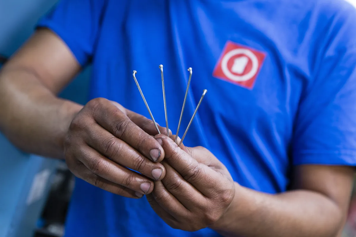 Hands of a Mach1 operator holding four J-bend steel spokes