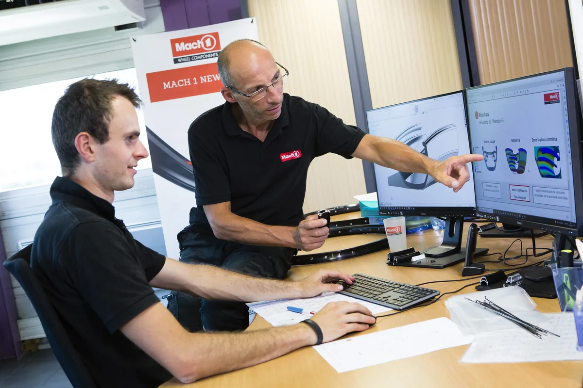 Due ingegneri Mach1 davanti agli schermi dell'ufficio tecnico, un cerchio in mano